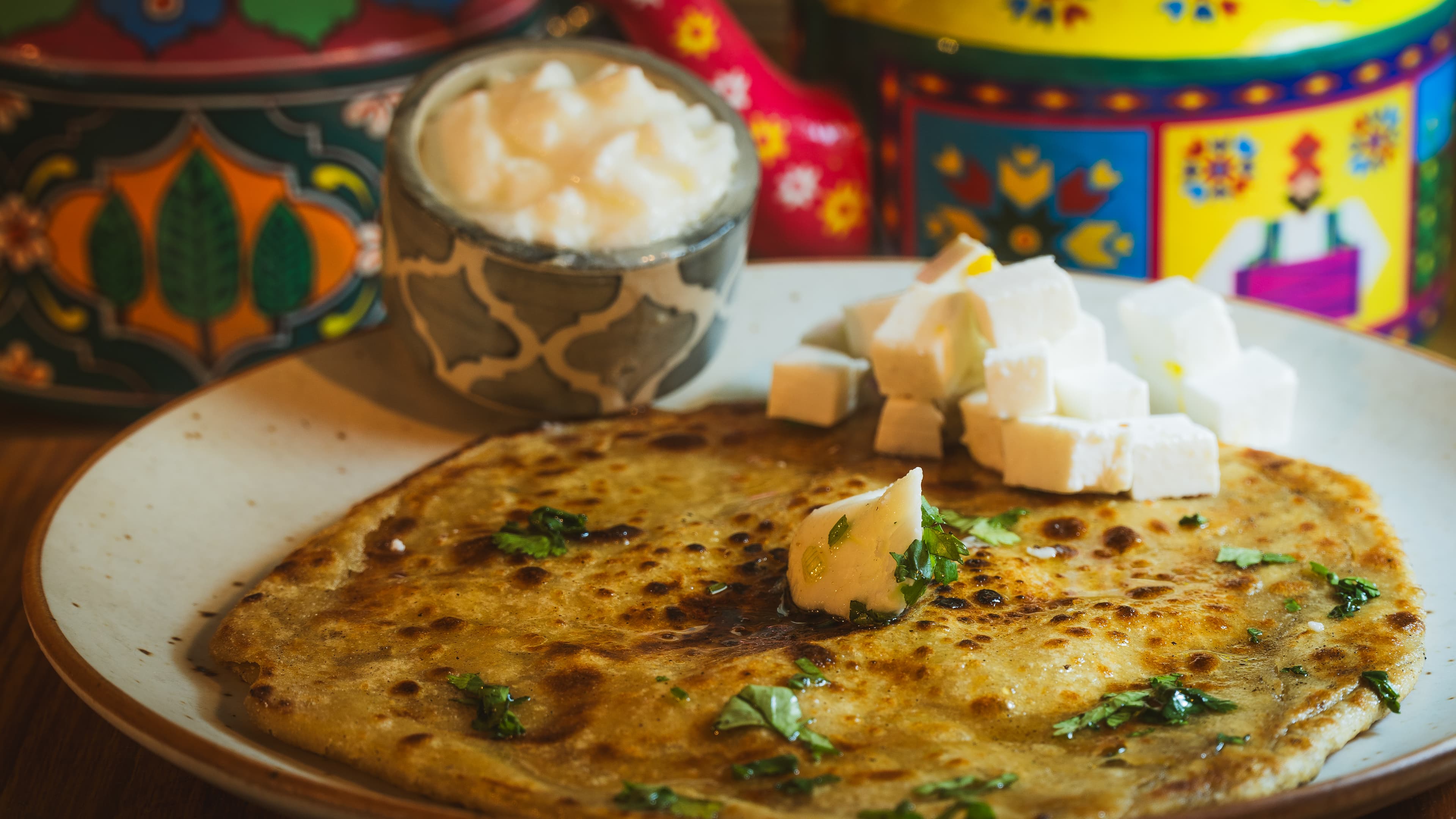 Buttery aloo paratha served with fresh curd and paneer cubes